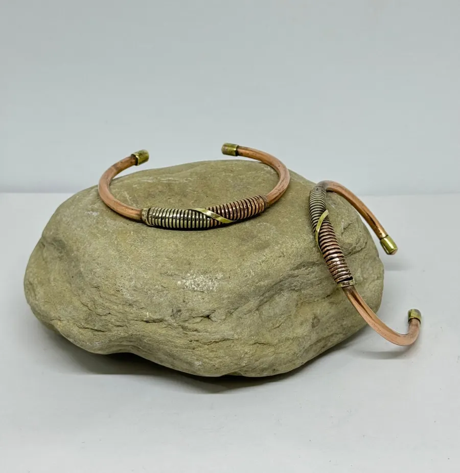 Hand-finished mixed-metal cuffs displayed on stone